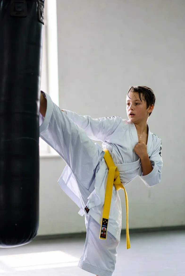 Yellow belt student throwing a high kick at a heavy bag
