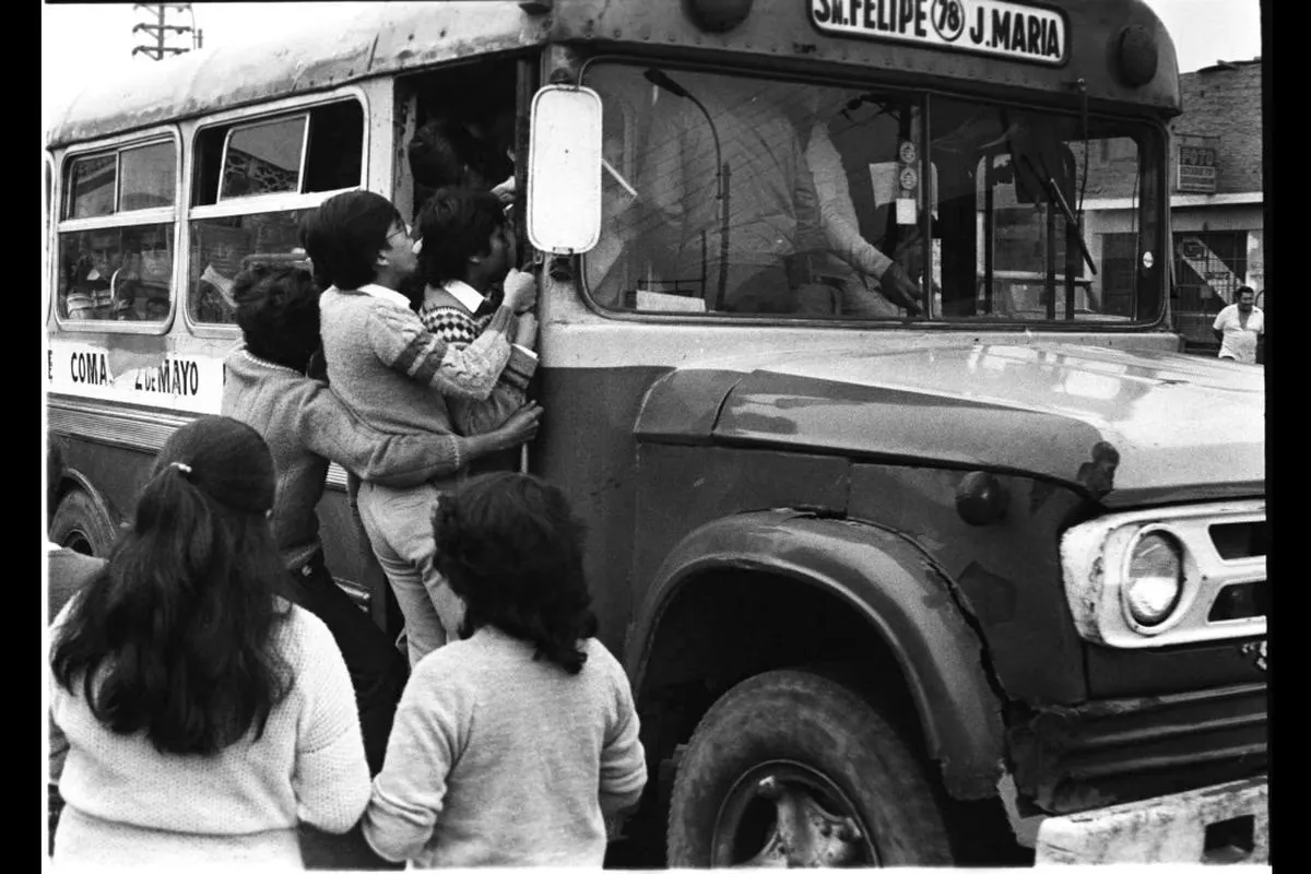 Black and white photo of children crowding into the doorway of an old city bus