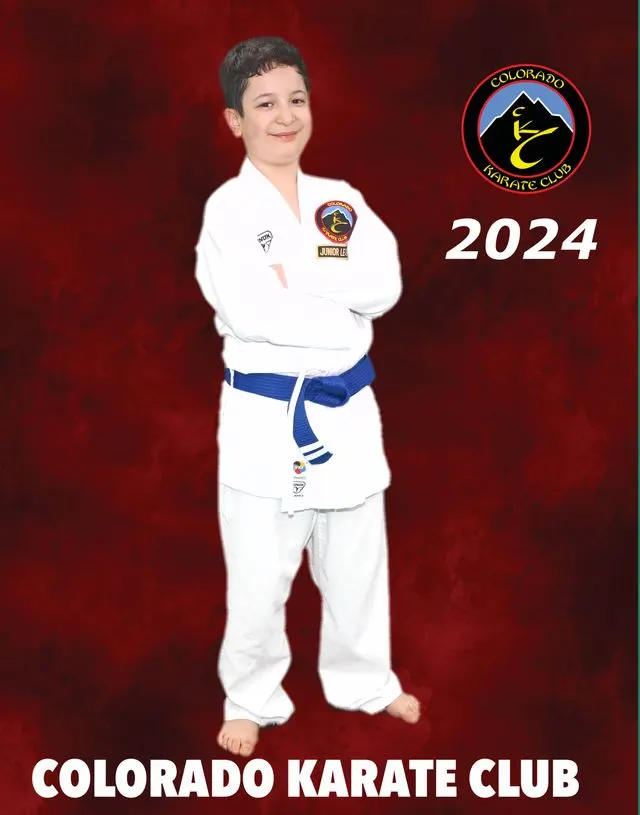 Smiling boy in a white gi and blue belt with arms crossed on a Colorado Karate Club 2024 poster